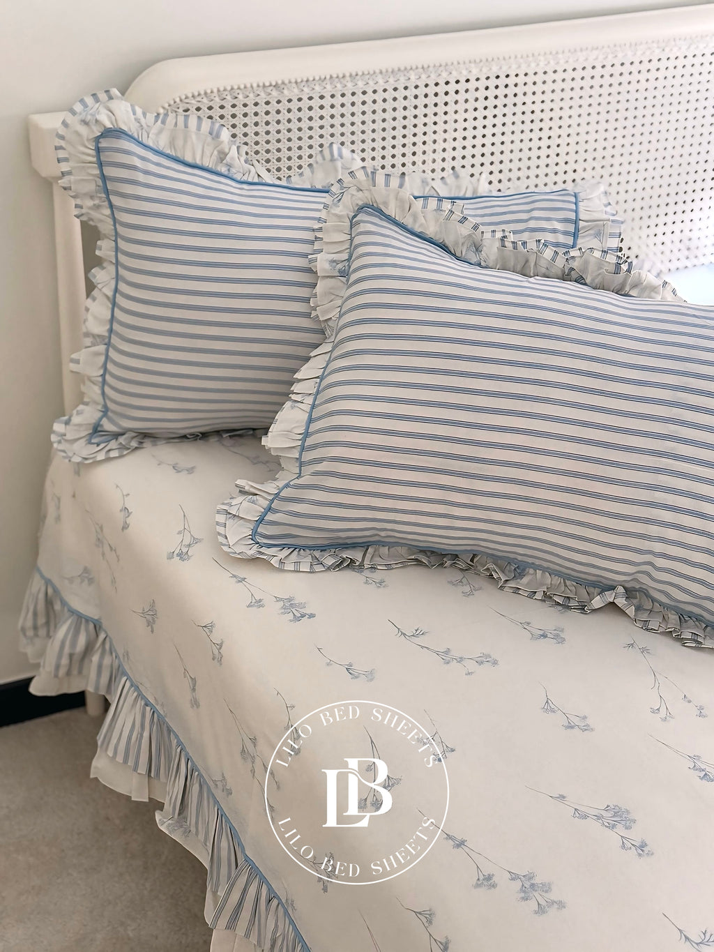 Striped pillows on a bed with a floral pattern, featuring the brand 'Lily Red Studio'.